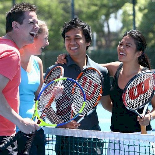 4 people on a tennis court chatting